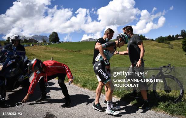 Team Bora rider Germany's Emanuel Buchmann is helped by a staff member after a crash during the fourth stage of the 72nd edition of the Criterium du...