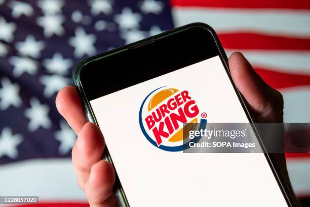 In this photo illustration the American chain of hamburger fast food restaurants Burger King logo is seen on an Android mobile device with United...