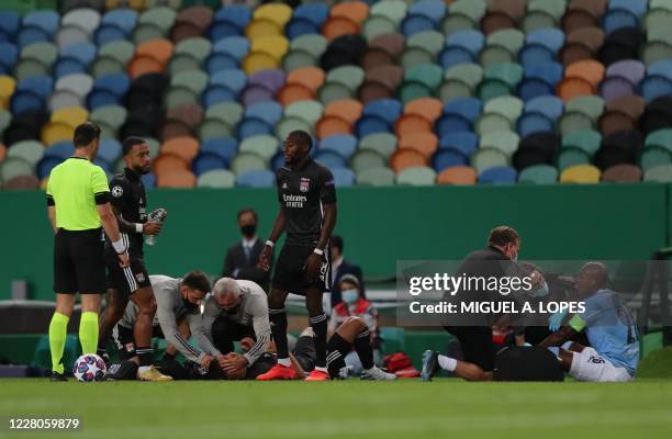 Lyon's French midfielder Houssem Aouar and Manchester City's Brazilian midfielder Fernandinho receive medical assitance after hitting their heads...