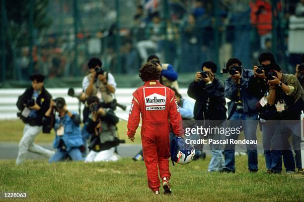 Photographers wait as Alain Prost of France, driver of the Marlboro McLaren-Honda MP4/5Honda RA109A V10 walks back to the pits after controversially...