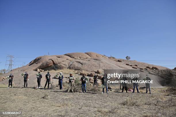 Mineworkers carry flowers as they arrive to the koppie in Marikana near Rustenburg on August 16, 2020 where striking miners were killed during the...