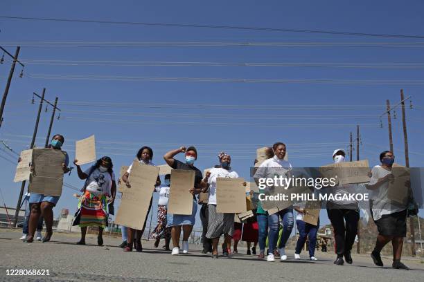 Women from Wonderkop informal settlement hold plackards as they march to the koppie in Marikana near Rustenburg on August 16, 2020 where striking...