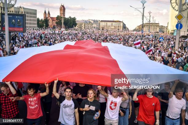 Belarus opposition supporters hold a giant former white-red-white flag of Belarus used in opposition to the government, during a demonstration in...