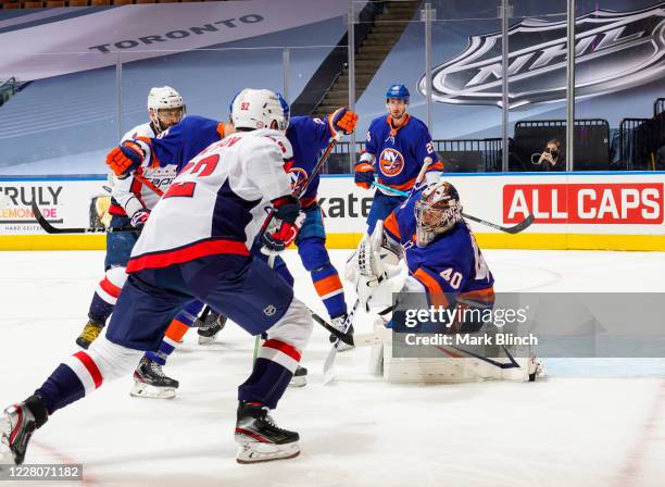 Semyon Varlamov of the New York Islanders makes a glove save asEvgeny Kuznetsov of the Washington Capitals goes to the net during the second period...