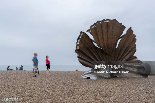 Families admire 'Scallop', a 4 metre high steel sculpture of two interlocking scallop shells on Aldeburgh beach dedicated to Benjamin Britten....