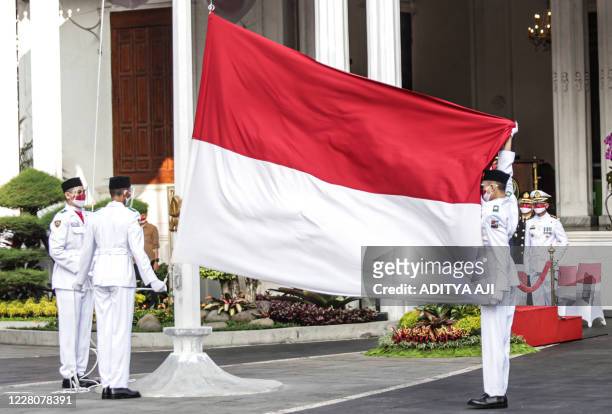 Facemask-clad personnel hoist the Indonesian national flag as part of commemorations marking the country's 75th Independence Day in Bogor, West Java...