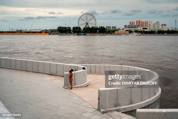 Woman stands on an embankment of the Amur river, with Chinese town of Heihe seen in the background, in the Russian far-eastern town of...