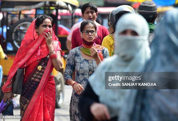 People walk and shop at a market in the old neighbourhood of Chowk, in Allahabad on August 17, 2020. - India's official coronavirus death toll soared...