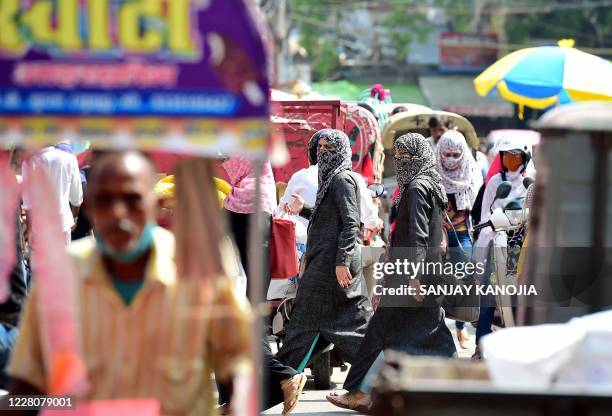 People walk and shop at a market in old neighborhood of Chowk, in Allahabad on August 17, 2020. - India's official coronavirus death toll soared past...