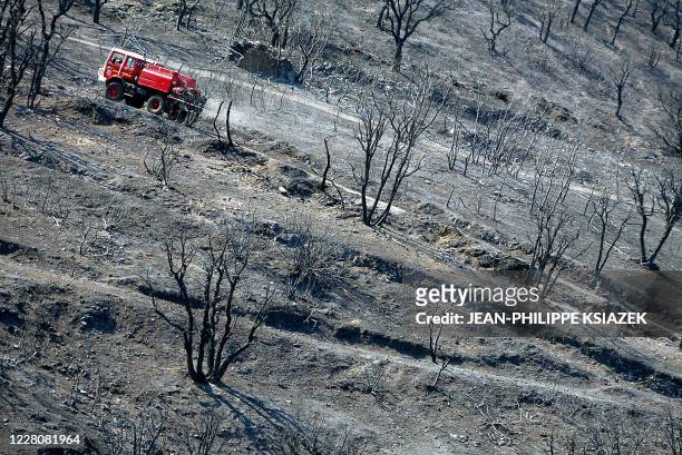 Un camion de pompier emprunte un chemin entre les arbres calcinés, le 30 juillet 2003 dans les environs de la Motte dans le Massif des Maures. Au...