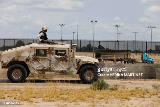 Members of the Mexican National Guard patrol along the banks of the Rio Grande by the construction site of a new section of the border wall between...