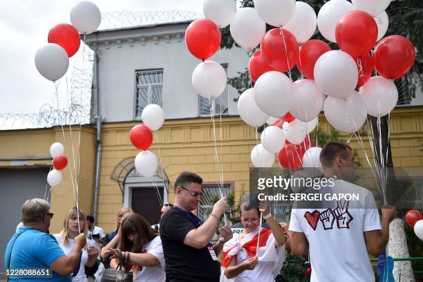 Opposition supporters holding white and red balloons gather outside a pre-trial detention centre, where Sergei Tikhanovsky - opposition figure...