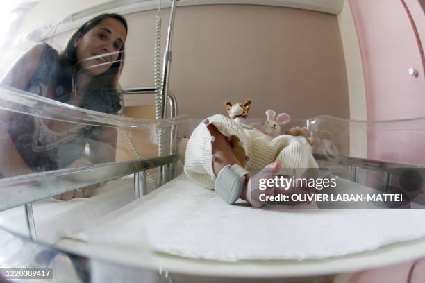 Une mère pose au côté de son enfant portant un bracelet électronique à la cheville le 11 avril 2007 à l'hôpital intercommunal du Raincy-Montfermeil....