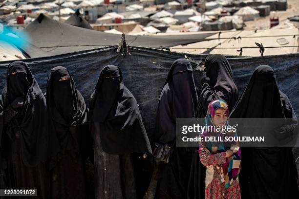 Girl stands in a line of women to receive aid at the Kurdish-run al-Hol camp in the al-Hasakeh governorate in northeastern Syria on August 18 where...