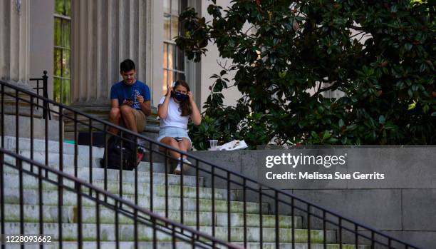 Person puts on a mask outside the closed Wilson Library at the campus of the University of North Carolina at Chapel Hill on August 18, 2020 in Chapel...