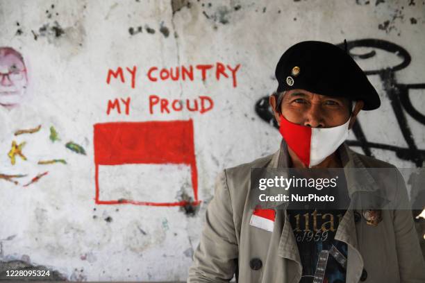 Bambang, pose wearing face mask pose for potrait photograph at his street paint studio during the celebration of Indonesia's 75th Independence Day in...