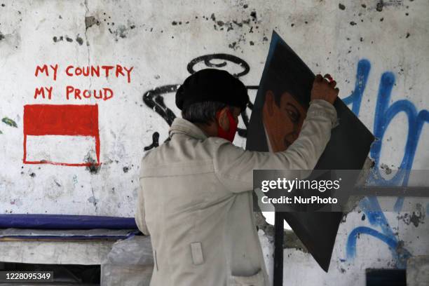 Bambang continue to paint a potrait of the Indonesian Founding Father, Sukarno at his street paint studio during the celebration of Indonesia's 75th...