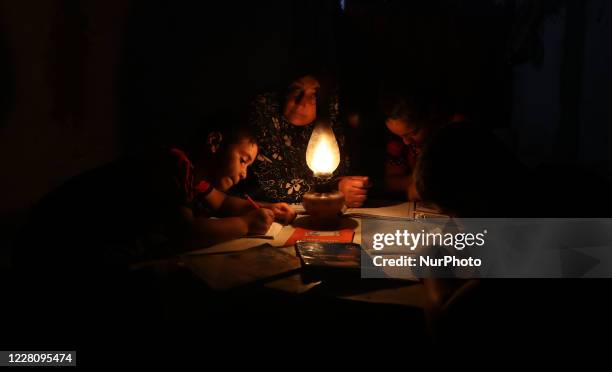 Palestinian children do their homeworks use gas lamps during a power cut after Gaza's lone power plant shut down amid tension with Israel, in Khan...