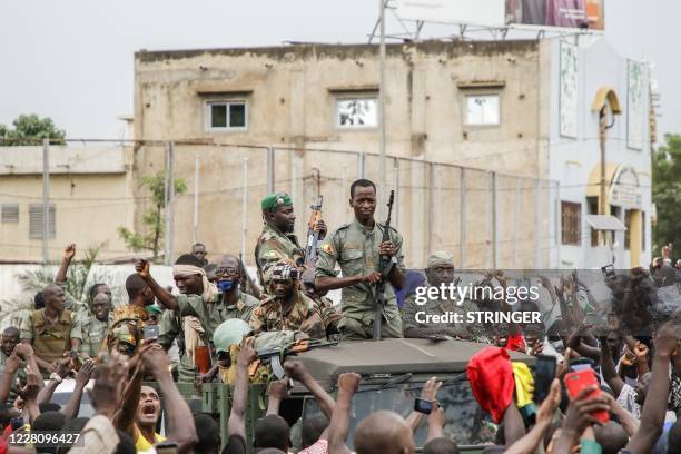 Armed members of the FAMA are celebrated by the population as they parade at Independence Square in Bamako on August 18 after rebel troops seized...