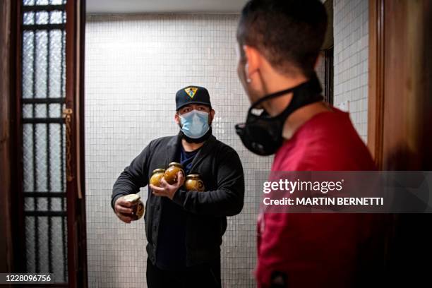 Chilean Matias Coussy , son of unemployment teacher Yohana Agurto, delivers jars of organic honey to a costumer in Santiago, on August 18, 2020. -...