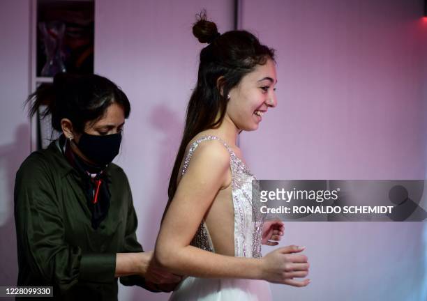 Argentinian Mia Minutillo is helped by her mother Veronica Riveira to put her quinceanera dress on, at their home in Buenos Aires, on July 30, 2020....