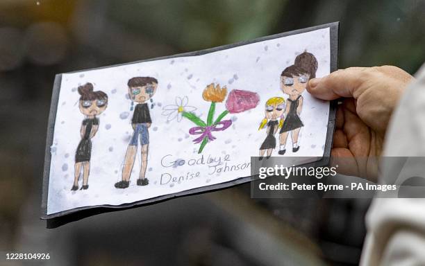 Person holds a drawing dedicated to singer Denise Johnson at her funeral outside Manchester Crematorium.