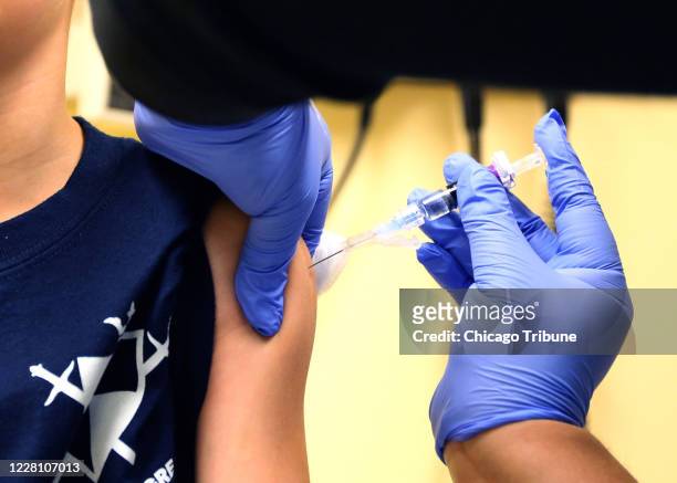 Johnathon Cabrera, de 8 años, recibe la vacuna contra la gripe de la asistente médica Gigi Hernández en el Advocate Children's Hospital, el jueves 29...