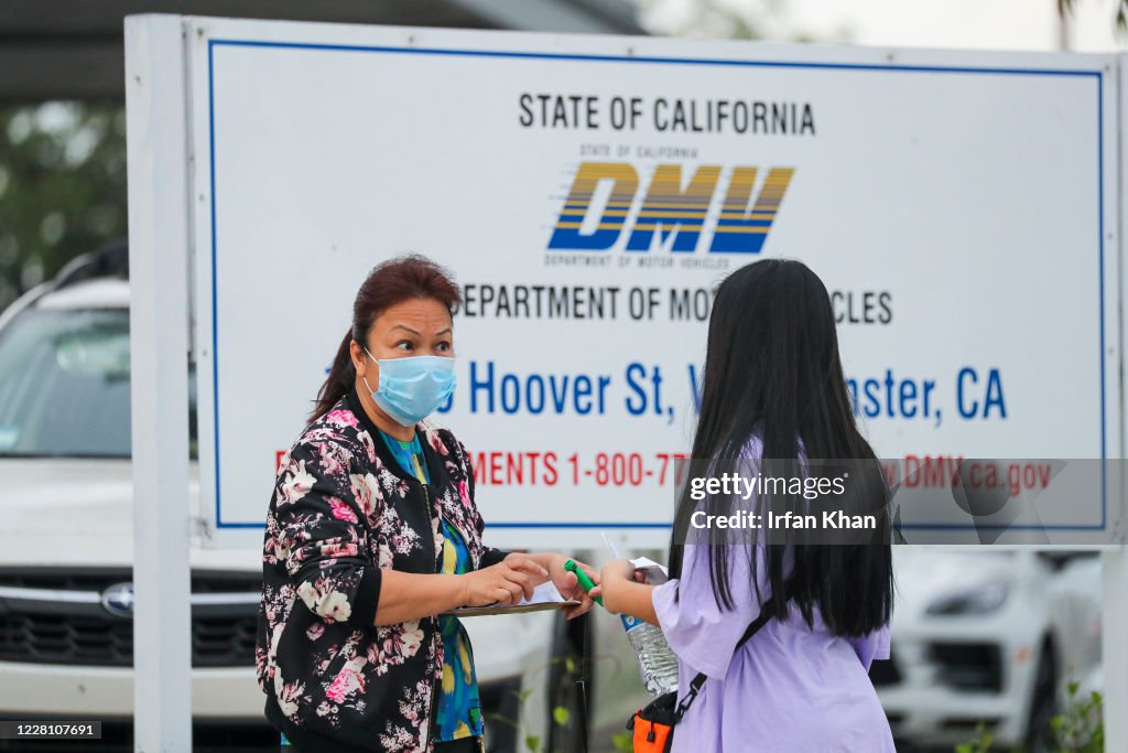 DMV staffer Kathy Cao left distributes numbers among the people DMV staffer Kathy Cao left distributes numbers among the people