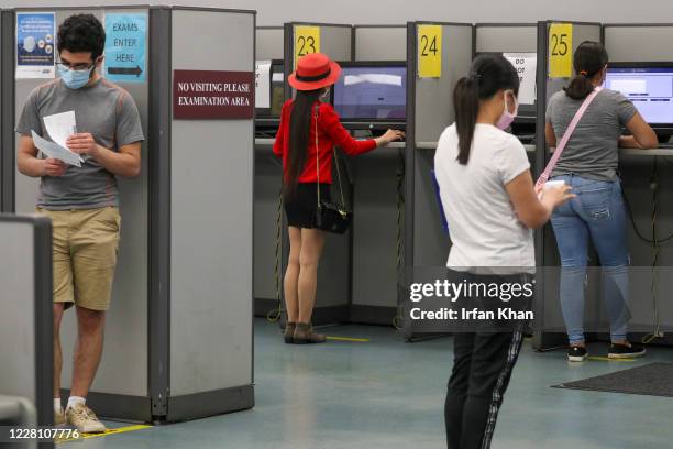 Clients observe social distancing while giving written driving test at DMV on Thursday, Aug. 13, 2020 in Westminster, CA.