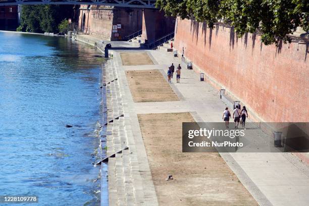 People walk on the river banks of the Garonne and all the grass is dead. The Garonne river is near its record low levels due to a lack of rain since...