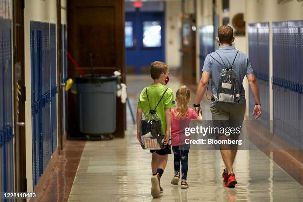 Student and parent wear backpacks, carrying a Google Chromebook laptop, left, and Apple Inc. Ipad tablet for remote learning, during a technology...