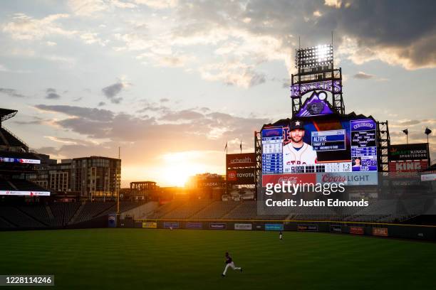 The sun sets over the stadium as Charlie Blackmon of the Colorado Rockies jogs after a foul ball during the third inning against the Houston Astros...