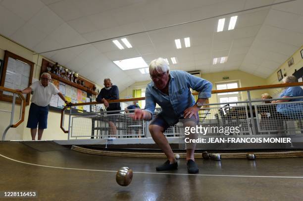 Player wearing slippers rolls a ball as he competes in the French western Anjou geographical region boules game "boule de fort", in the "Cercle des...