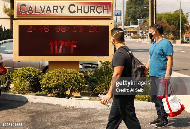 Anthony Aco and Troy Sacaguin, left to right, check out the thermometer at Calvary Church in Woodland Hills as it registers 117 degrees Fahrenheit...