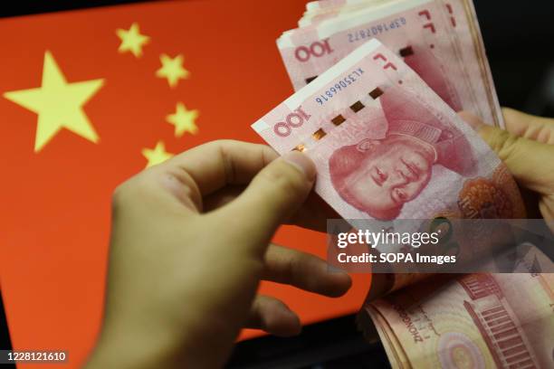 In this photo illustration a man counts 100 RMB notes with the Chinese flag in the background. In recent years, China has clamped down on shadow...