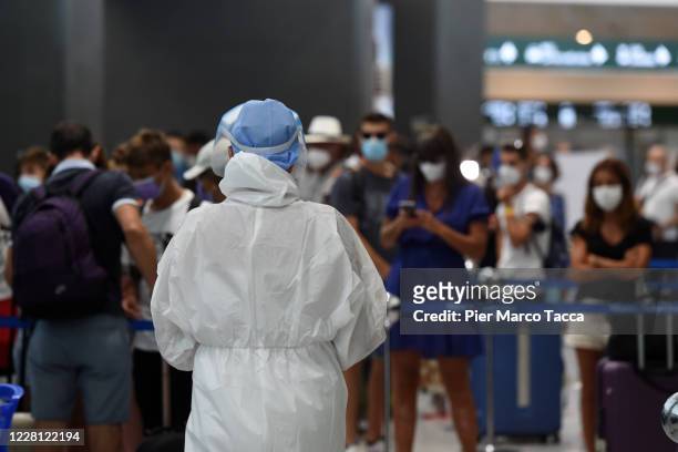 Healthcare worker attends the travelers for swabs Covid-19 testing at Malpensa Airport on August 20, 2020 in Somma Lombardo, Italy. From today, a...