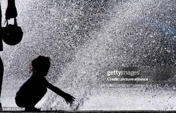 August 2020, Bavaria, Munich: A girl plays in a fountain at Stachus in the city centre. Photo: Peter Kneffel/dpa