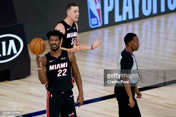 Jimmy Butler of the Miami Heat spins the ball as teammate Duncan Robinson argues a call with a referee against the Indiana Pacers in the first half...