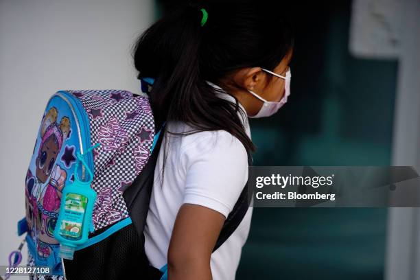 Student wearing a protective masks carries a bottle of hand sanitizer on her backpack while arriving to a public charter school in Provo, Utah, U.S.,...