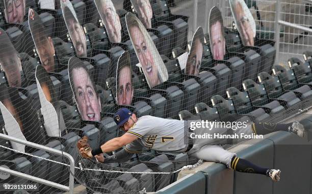 Eric Sogard of the Milwaukee Brewers falls into the empty seats after catching a foul ball hit by Ehire Adrianza of the Minnesota Twins during the...