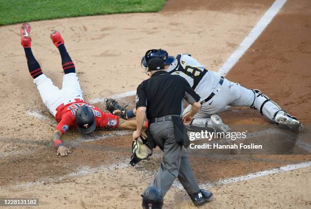 Manny Pina of the Milwaukee Brewers defends home plate against Eddie Rosario of the Minnesota Twins as umpire Jerry Meals looks on during the fourth...