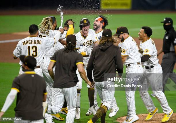 Jake Cronenworth of the San Diego Padres is congratulated by teammates after hitting an RBI single, allowing a run to score on an error in the 10th...