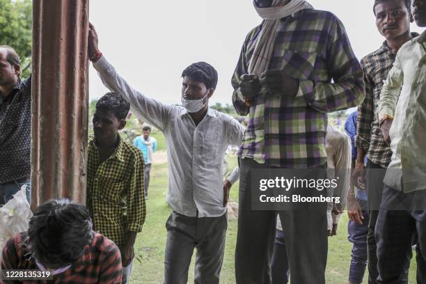 People wait in line to collect their subsidized ration of grain outside state-run distribution store in a village in Tikamgarh district, Madhya...