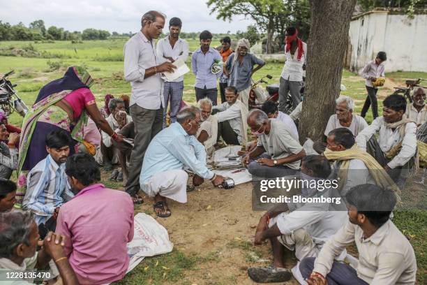 Man scans his thumb in an electronic point of sale machine near a state-run distribution store in a village in Tikamgarh district, Madhya Pradesh,...