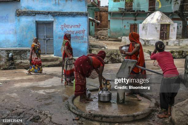 Women collect water from a community hand pump at a village in Tikamgarh district, Madhya Pradesh, India, on Friday, Aug. 7, 2020. Millions of...