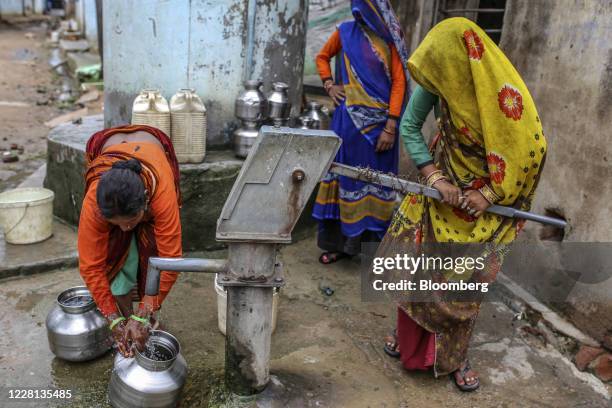 Women collect water from a community hand pump at a village in Tikamgarh district, Madhya Pradesh, India, on Friday, Aug. 7, 2020. Millions of...