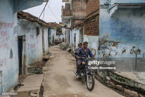 People ride a motorcycle through a village in Tikamgarh district, Madhya Pradesh, India, on Friday, Aug. 7, 2020. Millions of migrant workers made...