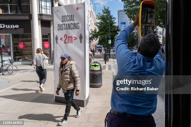 Bus driver adjusts his vehicle's left wing mirror on Oxford Street in the West End during the Coronavirus pandemic, on 20th August 2020, in London,...