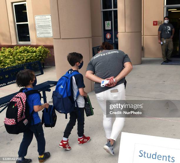 School employee escorts children as they return to school on the first day of in-person classes in Orange County at Baldwin Park Elementary School on...