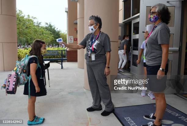 School employee checks the temperature of a student as she returns to school on the first day of in-person classes in Orange County at Baldwin Park...